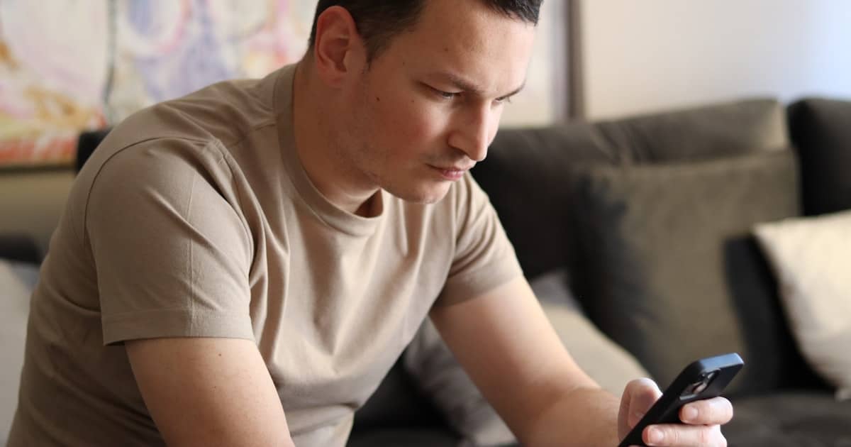 Pessoa com ar de preocupação olhando o celular após golpe do WhatsApp clonado com pedido de Pix