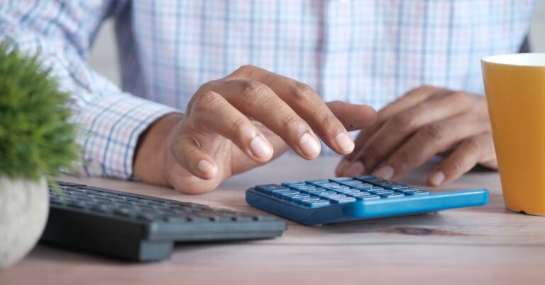Mão com calculadora e extrato bancário representando descontos e retenção de salário pelo Itaú