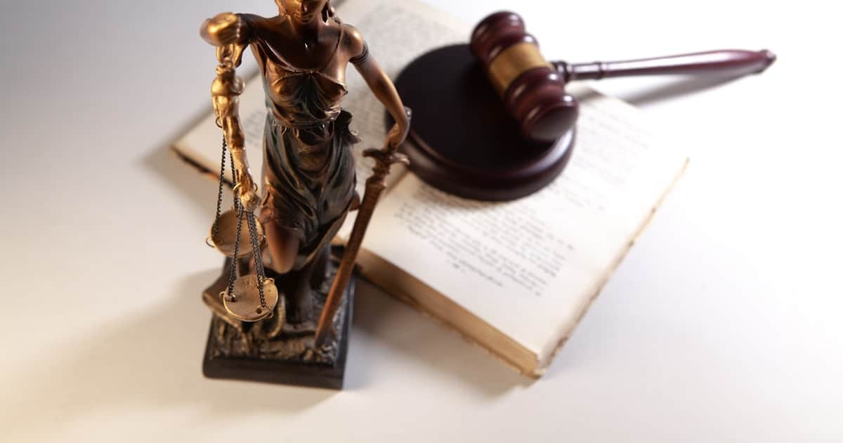 Estátua da justiça, martelo e livros representando decisões sobre negativação indevida