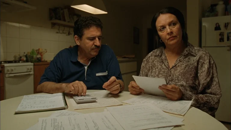 Casal à mesa da cozinha somando contratos de empréstimo e contas com a calculadora
