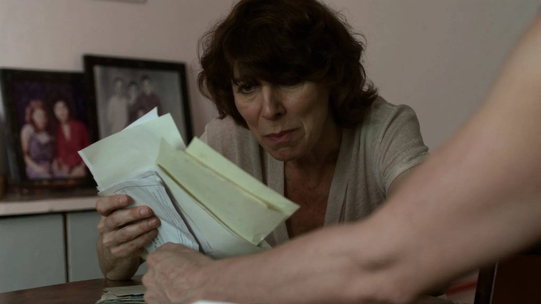 Filha organiza na mesa da cozinha os documentos e cartas de banco do pai falecido